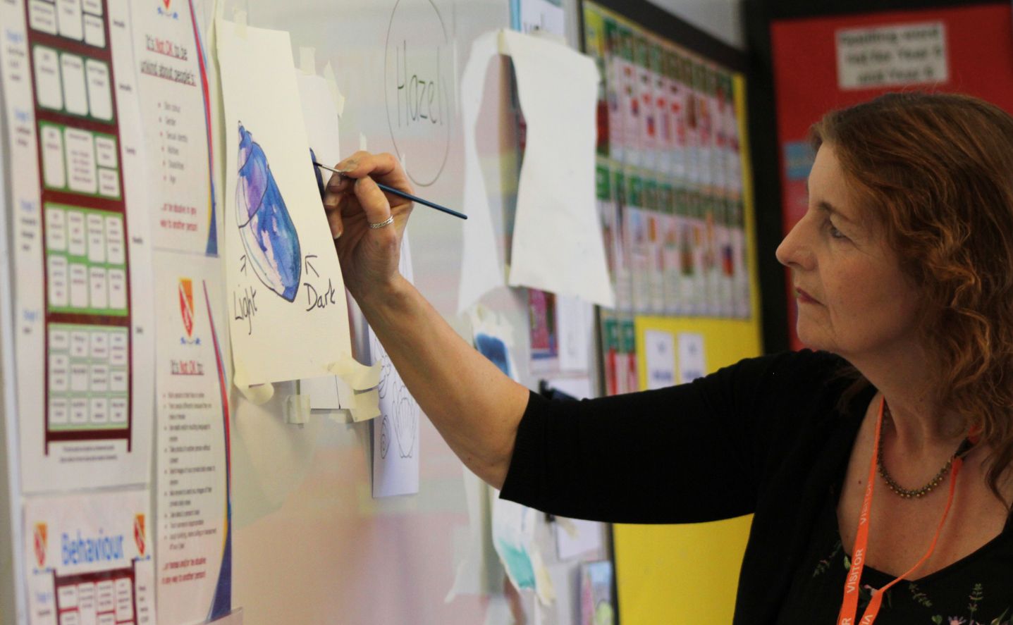A person holding a paintbrush at a whiteboard
